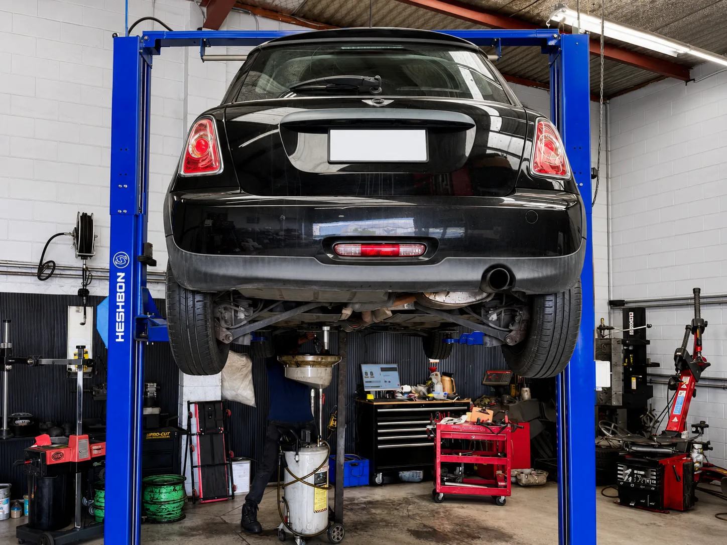 Black Mini raised on a vehicle hoist during a Warrant of Fitness inspection at PSM Workshop